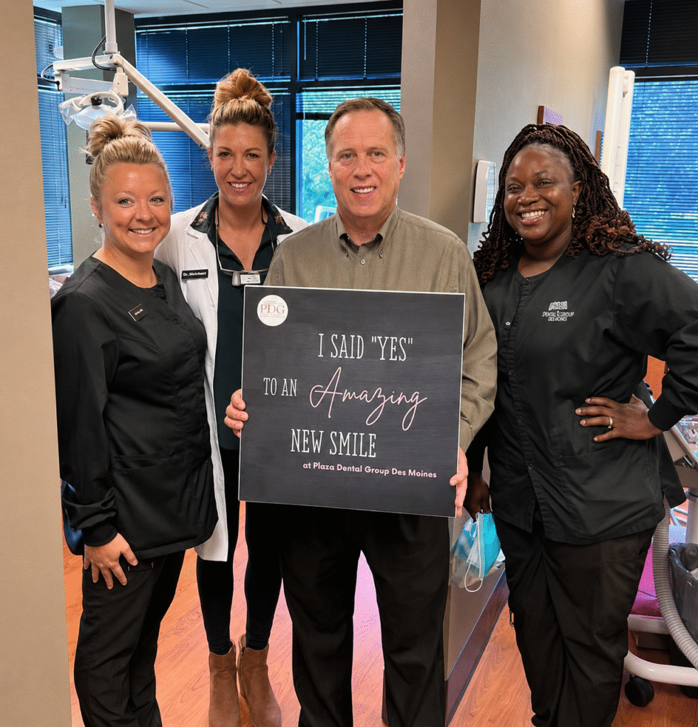 patient smiling with a sign that says " I said "yes" to an amazing smile" in the practice